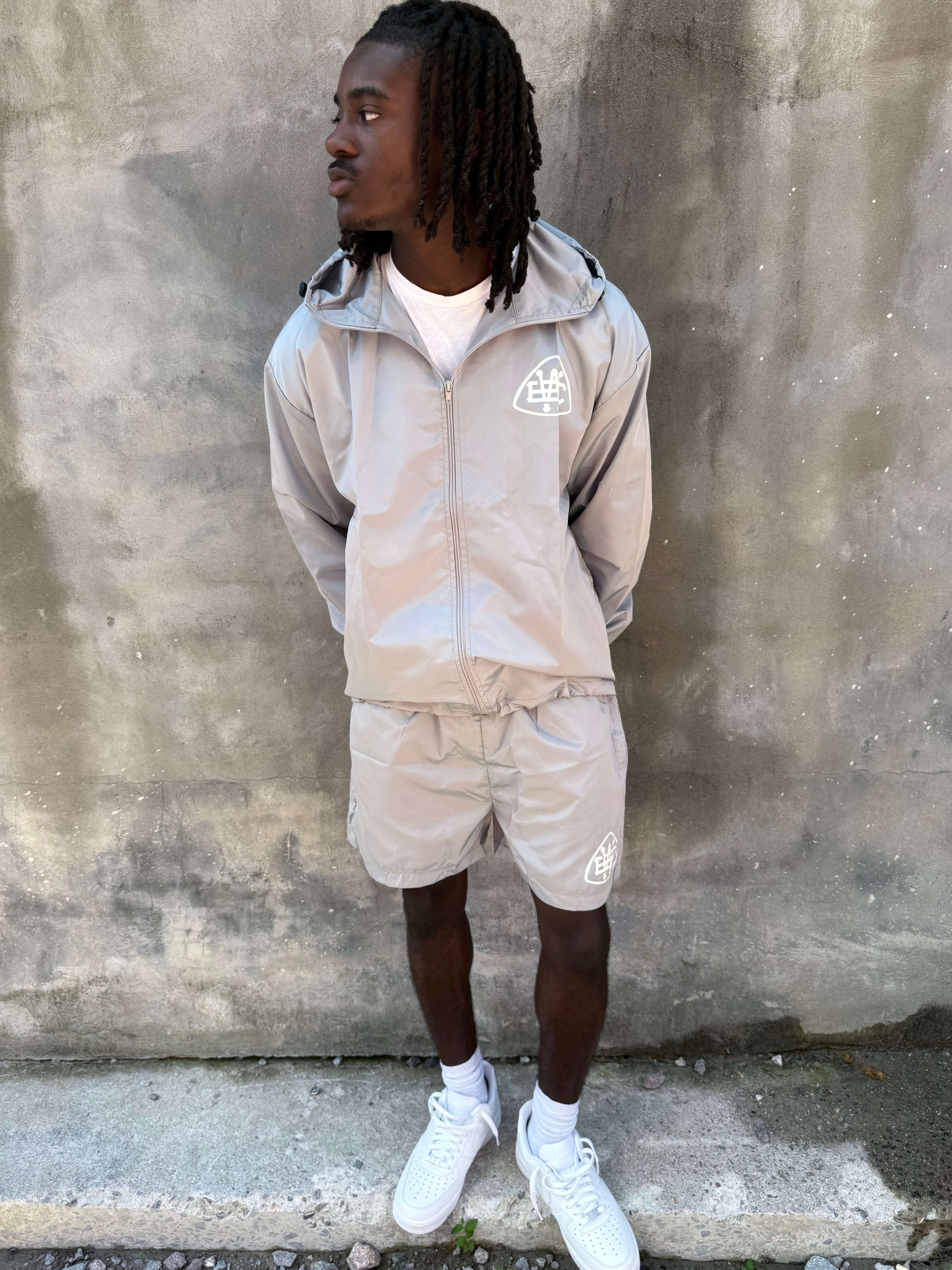 Man wearing Grey Unerring Set with drawstring hood and elastic cuffs, featuring bold white logos, stylish and true to size.