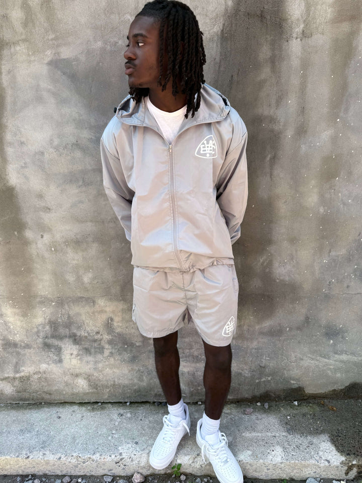 Man wearing Grey Unerring Set with drawstring hood and elastic cuffs, featuring bold white logos, stylish and true to size.