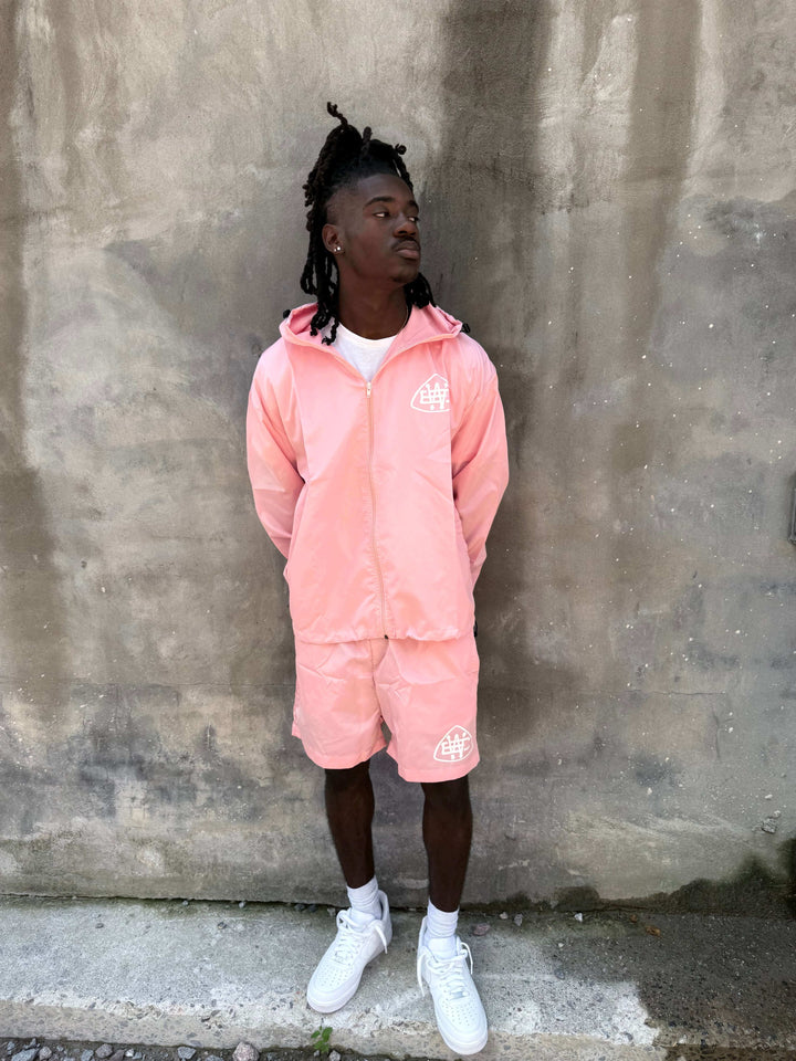 Model wearing a light pink Unerring Set with drawstring hood and bold white logo, perfect for stylish outfits.