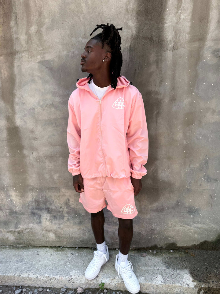 Light pink drawstring hooded set with elastic cuffs and bold white logo, perfect for casual wear.